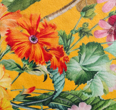 close up of meadow velvet lampshade in sunshine yellow, showing the bright yellow background, colourful flowers and green leaves