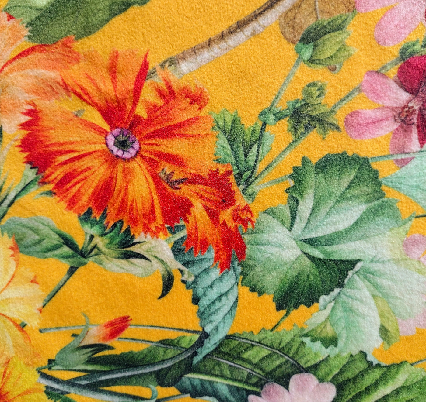 close up of meadow velvet lamp shade in sunshine yellow, showing the yellow background, colourful flowers and green leaves