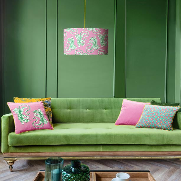 Candy pink tiger roar lampshade hanging in green living room with green sofa and matching tiger roar cushion